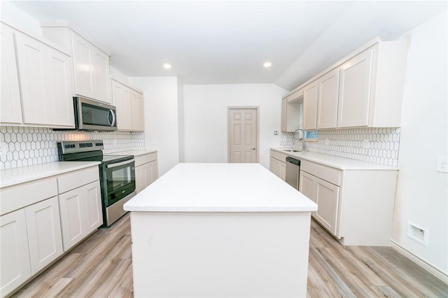 kitchen featuring stainless steel appliances, light hardwood / wood-style floors, white cabinets, and a kitchen island