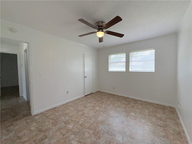 empty room featuring a ceiling fan, baseboards, and a textured ceiling