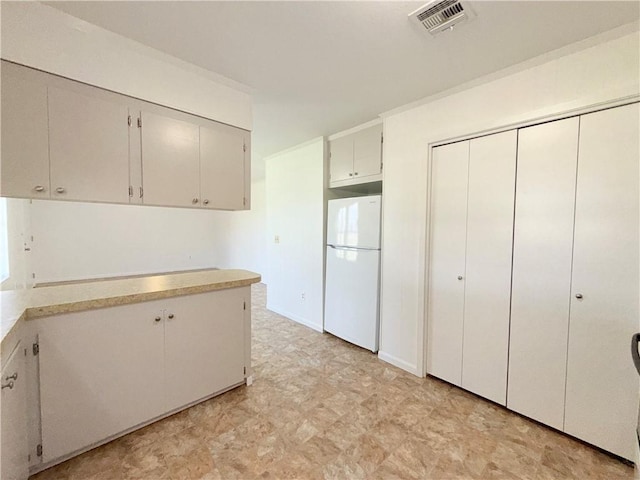 kitchen with light countertops, freestanding refrigerator, visible vents, and light floors