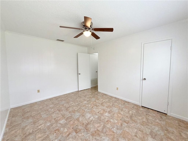 unfurnished bedroom featuring a ceiling fan, visible vents, a textured ceiling, and baseboards