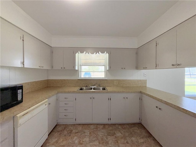 kitchen featuring black microwave, white dishwasher, a sink, white cabinetry, and light countertops