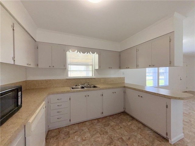 kitchen with black microwave, a sink, light countertops, dishwasher, and plenty of natural light