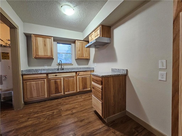 kitchen with a textured ceiling, light stone counters, sink, and dark hardwood / wood-style floors