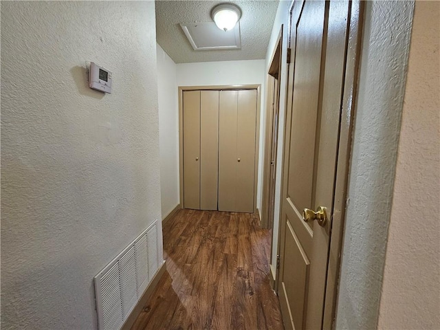 corridor featuring a textured ceiling and dark hardwood / wood-style floors