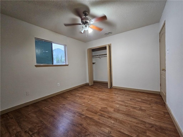 unfurnished bedroom with ceiling fan, a closet, a textured ceiling, and hardwood / wood-style flooring