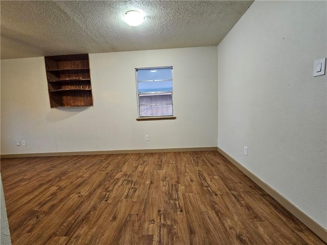 empty room featuring a textured ceiling and hardwood / wood-style flooring