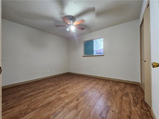 empty room with ceiling fan, wood-type flooring, and a textured ceiling