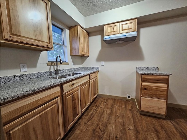 kitchen featuring a textured ceiling, dark hardwood / wood-style floors, dark stone countertops, and sink