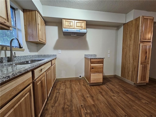 kitchen with a textured ceiling, dark hardwood / wood-style floors, dark stone countertops, and sink