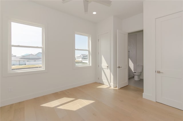 unfurnished bedroom with ceiling fan, multiple windows, light hardwood / wood-style floors, and ensuite bath