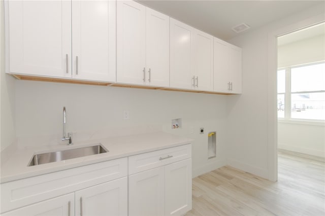 laundry area featuring hookup for an electric dryer, cabinets, sink, light hardwood / wood-style flooring, and hookup for a washing machine