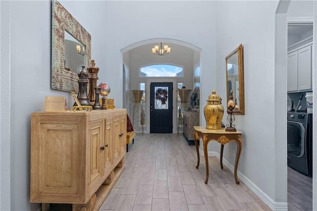 entrance foyer featuring light wood-type flooring, a chandelier, and washer / dryer