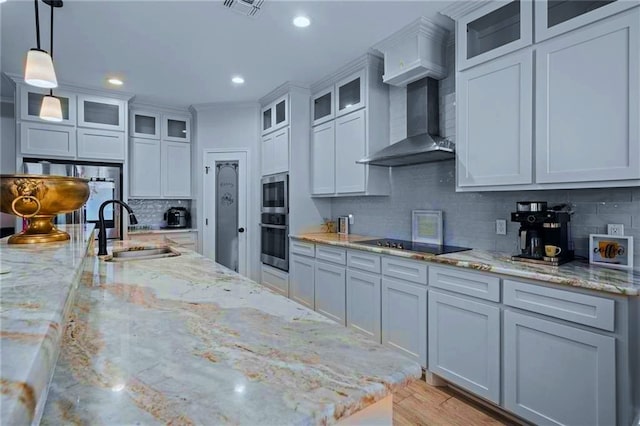 kitchen with sink, tasteful backsplash, light stone countertops, decorative light fixtures, and wall chimney range hood