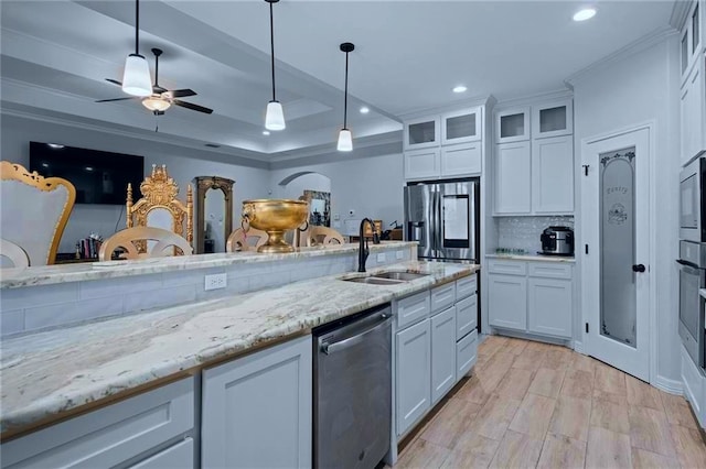 kitchen featuring stainless steel appliances, white cabinetry, decorative light fixtures, light stone countertops, and sink