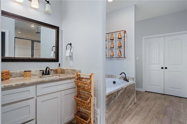 bathroom with hardwood / wood-style floors, vanity, and independent shower and bath