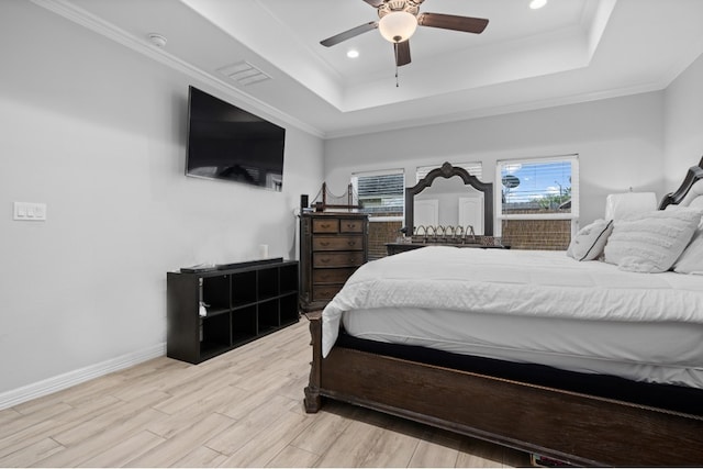 bedroom with ornamental molding, a tray ceiling, light hardwood / wood-style floors, and ceiling fan