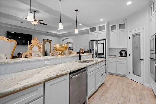 kitchen featuring stainless steel appliances, crown molding, decorative light fixtures, sink, and white cabinets