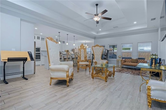 living room with ornamental molding, a raised ceiling, light hardwood / wood-style floors, a high ceiling, and ceiling fan with notable chandelier