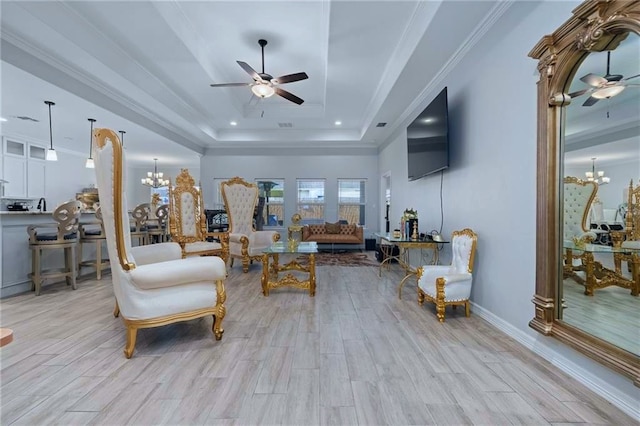 living room with ornamental molding, a tray ceiling, light hardwood / wood-style floors, and ceiling fan with notable chandelier