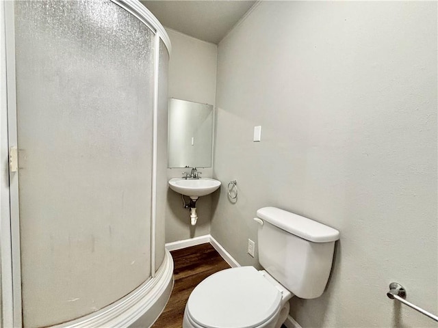 full bathroom featuring toilet, a sink, a shower stall, wood finished floors, and baseboards