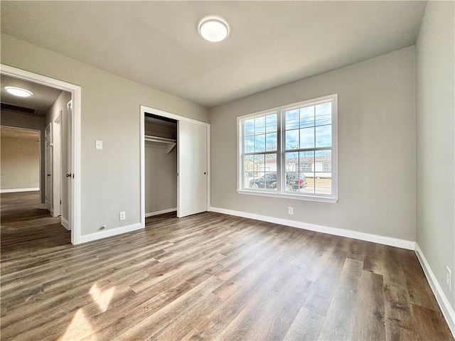 unfurnished bedroom with a closet, wood finished floors, and baseboards