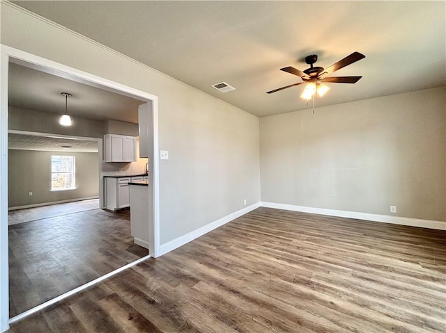 spare room with a ceiling fan, baseboards, and wood finished floors