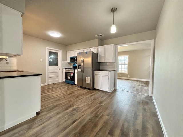 kitchen featuring range with gas stovetop, dark countertops, visible vents, white cabinetry, and stainless steel fridge with ice dispenser