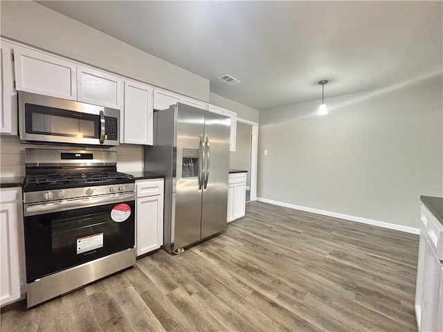 kitchen with stainless steel appliances, wood finished floors, visible vents, white cabinets, and dark countertops