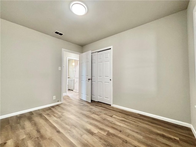 unfurnished bedroom featuring baseboards, visible vents, and wood finished floors