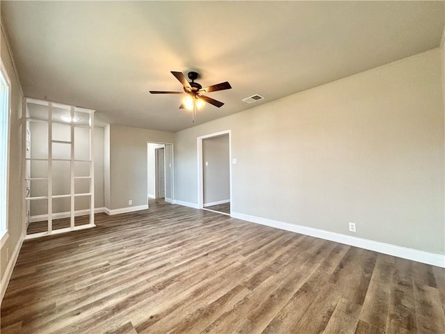 spare room featuring a ceiling fan, baseboards, visible vents, and wood finished floors