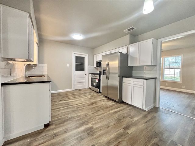 kitchen featuring dark countertops, visible vents, appliances with stainless steel finishes, and a sink