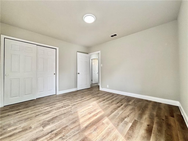 unfurnished bedroom with visible vents, baseboards, and wood finished floors