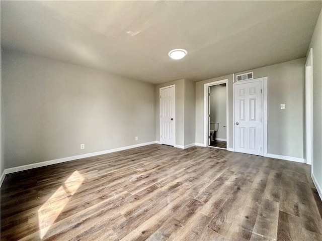 spare room with dark wood finished floors, visible vents, and baseboards