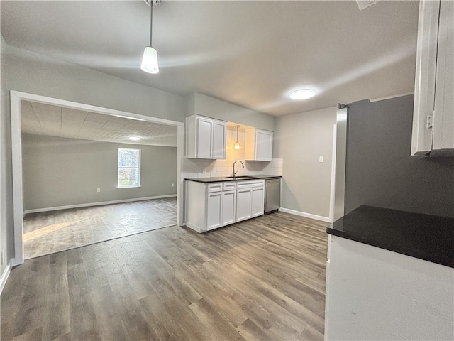 kitchen featuring dark countertops, open floor plan, dishwasher, and a sink