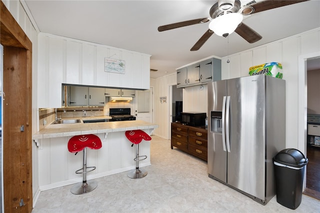 kitchen with kitchen peninsula, sink, stainless steel fridge with ice dispenser, a kitchen breakfast bar, and black stove