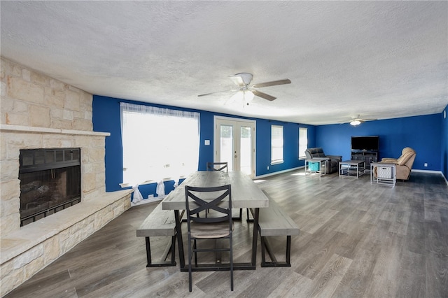 dining room with hardwood / wood-style floors, a fireplace, a textured ceiling, and ceiling fan