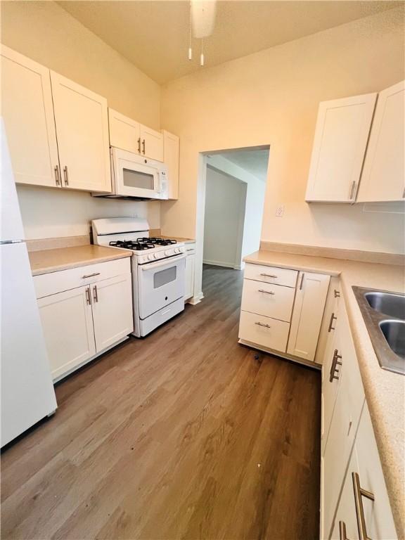 402 E Nopal St, Rockport, TX 78382 - kitchen featuring wood finished floors, white appliances, light countertops, white cabinets, and a sink