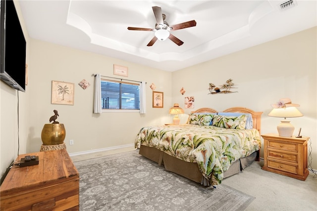 carpeted bedroom with ceiling fan and a tray ceiling