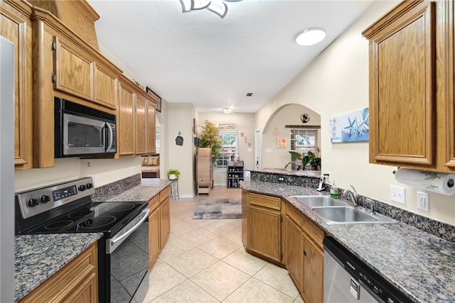 13706 Sea Horse Ave, Corpus Christi, TX 78418 - kitchen featuring stainless steel appliances, light tile patterned floors, dark countertops, a peninsula, and brown cabinets