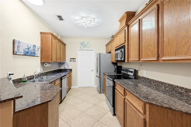 13706 Sea Horse Ave, Corpus Christi, TX 78418 - kitchen featuring stainless steel appliances, light tile patterned floors, a peninsula, dark stone counters, and brown cabinets
