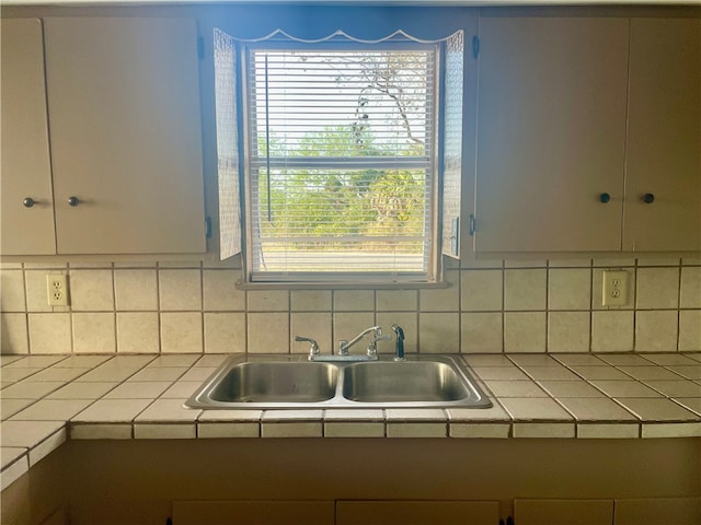 kitchen featuring decorative backsplash, a wealth of natural light, sink, and tile counters