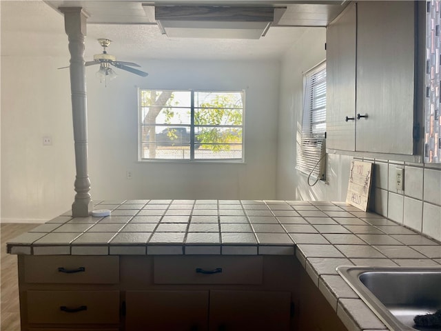 kitchen featuring tasteful backsplash, tile countertops, ceiling fan, and light hardwood / wood-style floors