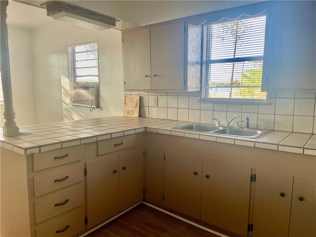 kitchen with backsplash, tile counters, sink, and dark wood-type flooring