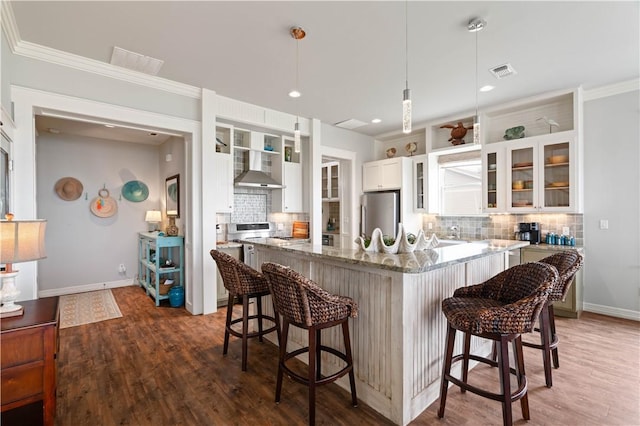 502 Sailhouse Way, Rockport, TX 78382 - kitchen featuring backsplash, visible vents, wall chimney range hood, freestanding refrigerator, and a kitchen bar