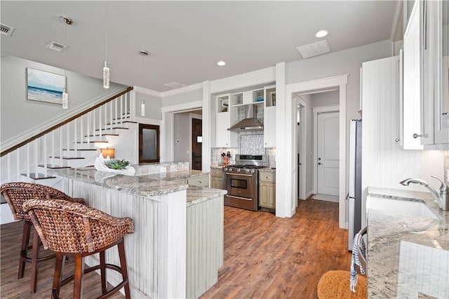502 Sailhouse Way, Rockport, TX 78382 - kitchen with light wood finished floors, a kitchen breakfast bar, a sink, wall chimney range hood, and stainless steel range