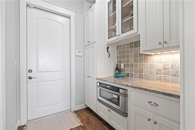 502 Sailhouse Way, Rockport, TX 78382 - kitchen featuring white cabinets, light stone countertops, decorative backsplash, glass insert cabinets, and dark wood-style flooring