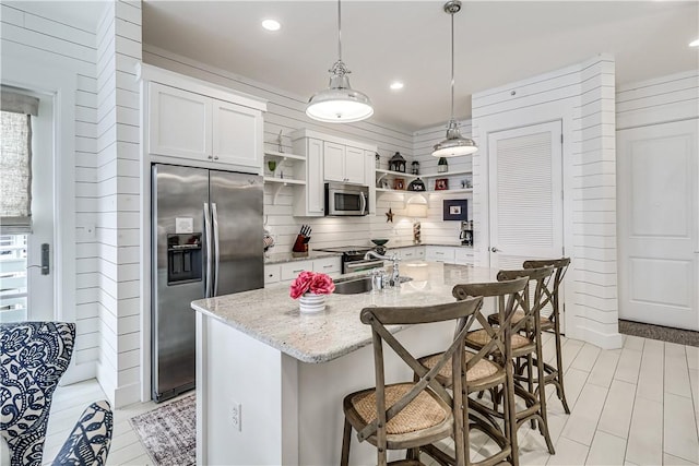 kitchen featuring a breakfast bar, open shelves, tasteful backsplash, appliances with stainless steel finishes, and light stone countertops