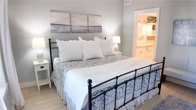 bedroom featuring light wood-style flooring, baseboards, and connected bathroom
