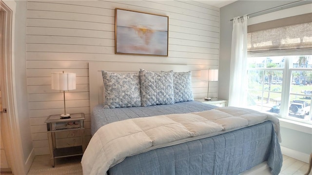 bedroom with wooden walls, multiple windows, and baseboards