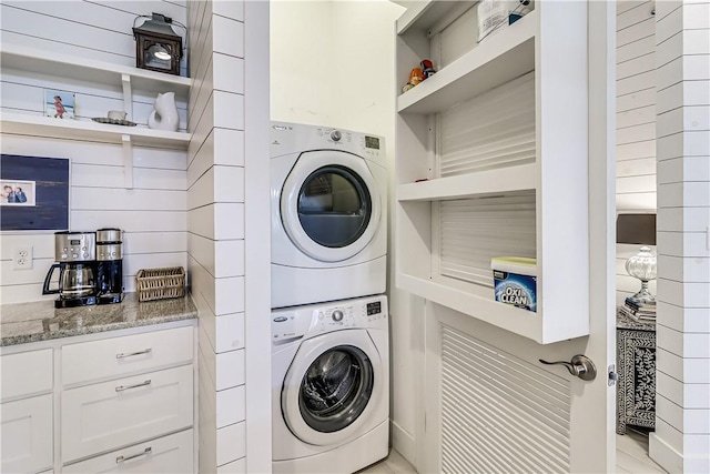 laundry area with laundry area, built in shelves, and stacked washer and clothes dryer